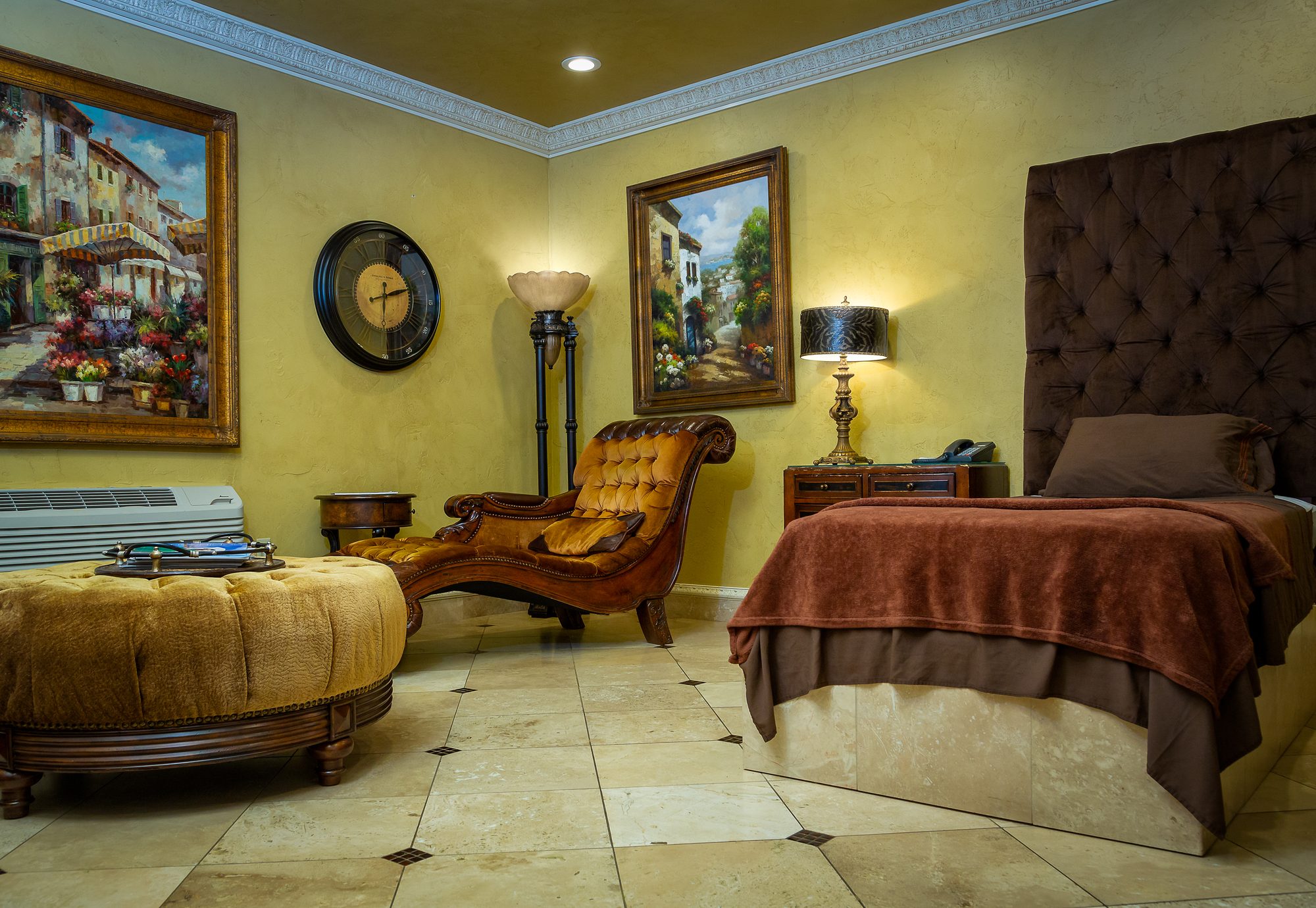 A patient suite at the Tulsa Surgical Arts villa with a bed, chaise, and lamp-lit seating